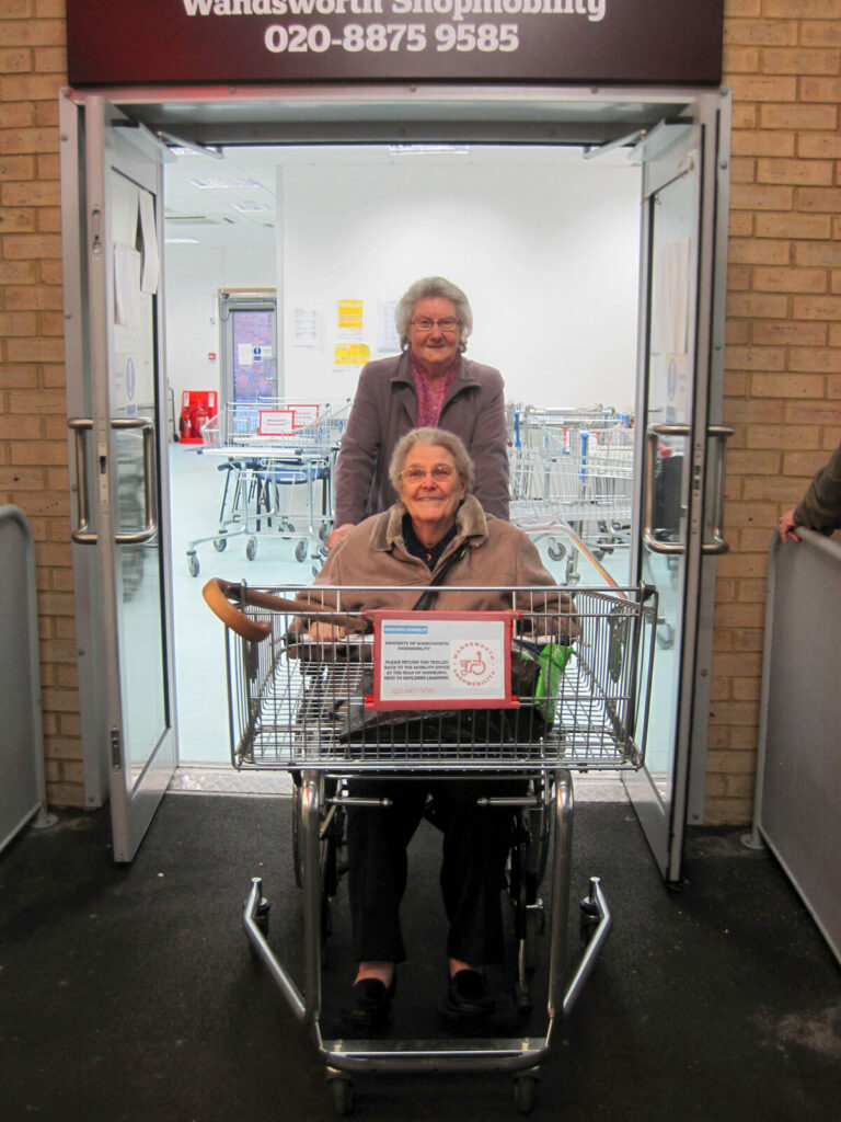 Shopper and helper coming out of Wandsworth Shopmobility entrance